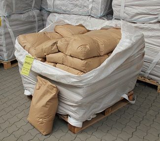Effizienter Schlackenbinder SPORLIT für den Eisen- und Stahlguss mit Produktetikett und einzelnem Papiersack vor einem Big Bag